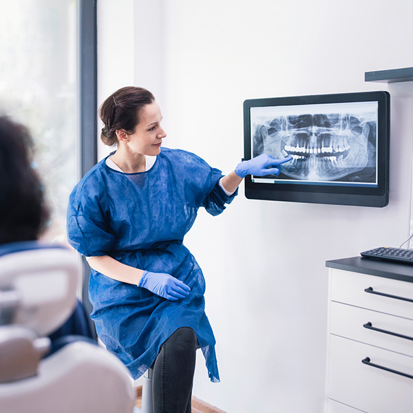 Female dentist explaining tooth x-rays to a unrecognizable patient